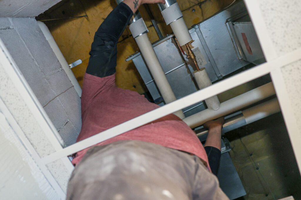 Plumber installing valve on copper pipe as part of commercial HVAC & plumbing system upgrade